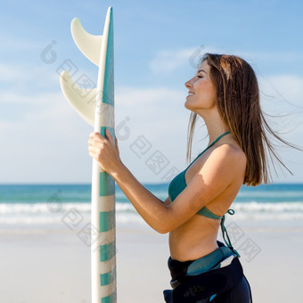 美丽的冲浪者女孩的海滩持有冲浪板