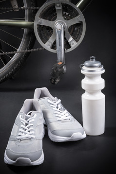 自行车与运动鞋和瓶水黑色的背景
