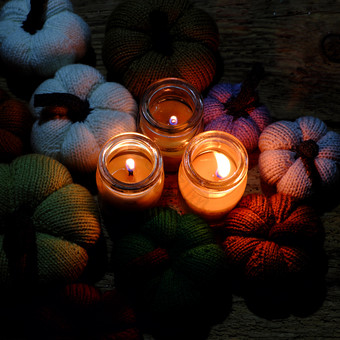 美丽的针织南瓜从纱与三个蜡烛晚上蜡烛光使色彩斑斓的背景不错的手工制作的产品从休闲活动