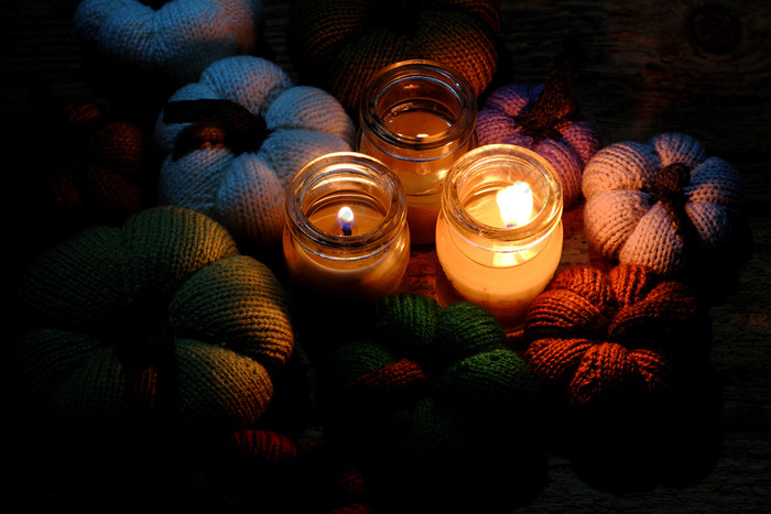 美丽的针织南瓜从纱与三个蜡烛晚上蜡烛光使色彩斑斓的背景不错的手工制作的产品从休闲活动