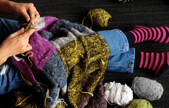 亚洲女人坐地板上首页针织羊毛毯子为温暖的冬季针织爱好休闲活动使手工制作的礼物照片女人手工作从前视图一天
