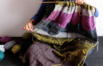 亚洲女人坐地板上首页针织羊毛毯子为温暖的冬季针织爱好休闲活动使手工制作的礼物照片女人手工作从前面视图一天