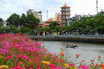 谁警察局城市越南NAM-4月两个环境卫生工人坐船和移动运河一天景观与叶子花属花前景和宝塔背景
