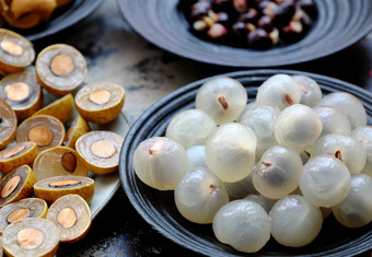 前视图越南热带甜蜜的水纸浆水果关闭龙眼的水果肉半透明的白色黑色的板与黑色的种子黄色的皮减少一半龙眼睛水果背景
