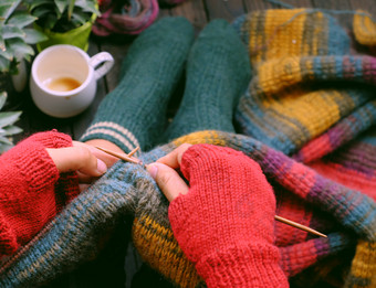 前视图女人脚与袜子坐着首页阳台手与针织手套持有针织针针织色彩斑斓的羊毛围巾为有意义的手工制作的冬天礼物当冬季来