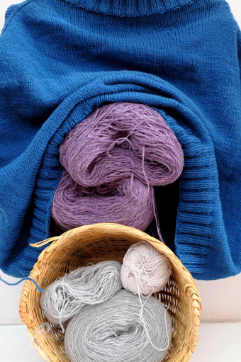 手工制作的产品为冬天季节礼物球纱材料针织竹子篮子男人。蓝色的毛衣挂白色背景手工艺与羊毛衣服冷季节年越南