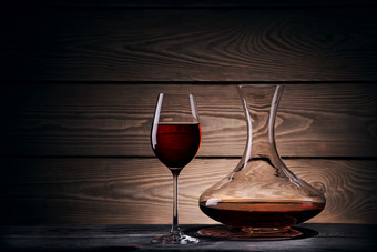 玻璃水瓶和玻璃与红色的酒木表格与黑暗背景玻璃水瓶和玻璃与红色的酒木表格