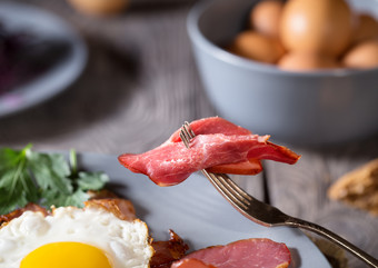 一块美味的培根叉在板与鸡蛋的概念健康的自然营养特写镜头一块美味的培根叉在板与鸡蛋