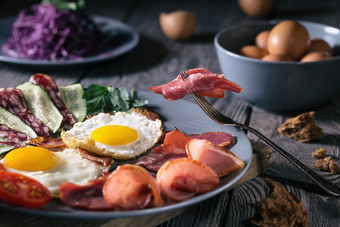炸鸡蛋与培根和蔬菜蓝色的板仍然生活乡村风格的概念简单的和健康的食物炸鸡蛋与培根和蔬菜蓝色的板