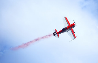 红色的和白色飞机发射彩色的烟的天空的概念运动和自由红色的和白色飞机发射彩色的烟的天空