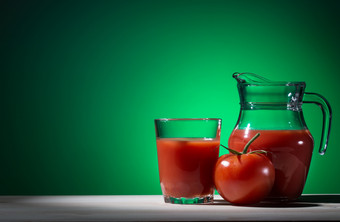 番茄玻璃和壶番茄汁绿色背景的概念健康的自然营养番茄玻璃和壶番茄汁绿色背景