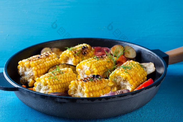 玉米和蔬菜烤煎锅蓝色的背景视图从以上的概念健康的自然食物玉米和蔬菜烤煎锅
