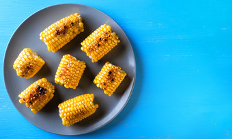 灰色的板与烤玉米蓝色的背景视图从以上的概念健康的自然食物灰色的板与烤玉米