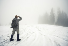 男人。与背包的冬天山同行成的多雾的距离冬天景观的概念自由旅行和选择方法男人。与背包的冬天山同行成的多雾的