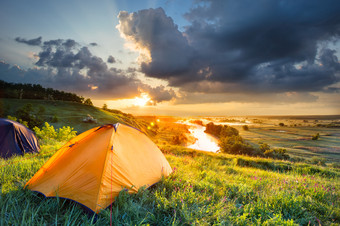 明亮的橙色帐篷的山坡上下面的河橙色帐篷前山下哪一个<strong>河流</strong>的概念自由和旅行