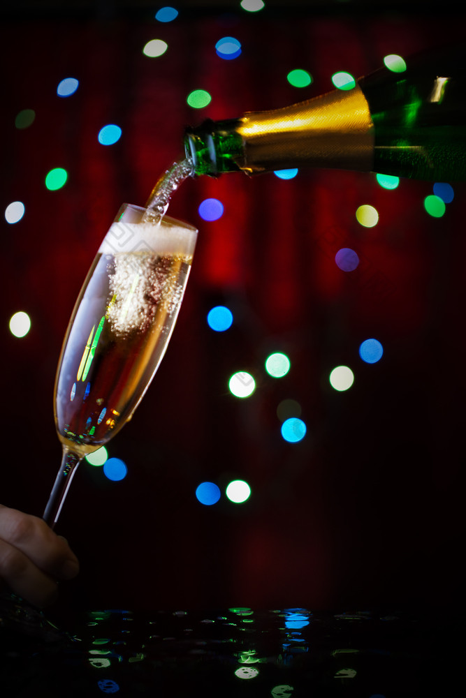 香槟倒成玻璃从瓶散景花环的概念庆祝的新一年和圣诞节香槟倒成玻璃从瓶
