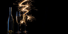 眼镜和瓶香槟的节日火花孟加拉灯黑色的背景的概念庆祝圣诞节婚礼复制空间眼镜和瓶香槟的节日火花孟加拉