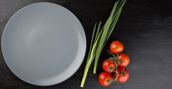 灰色的空粘土菜黑色的背景视图从以上关闭西红柿和洋葱的地方为的登记灰色的空粘土菜黑色的背景