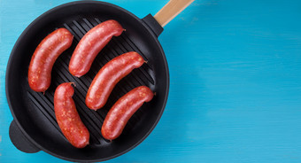 肉多汁的香肠铸铁煎锅蓝色的背景的概念自然传统的食物肉多汁的香肠煎锅蓝色的背景