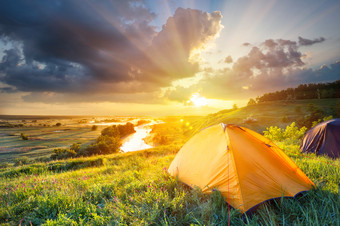 橙色帐篷山坡上的明亮的<strong>太阳</strong>橙色帐篷前山下哪一个<strong>河流</strong>的概念自由和旅行