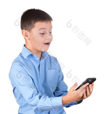 男孩蓝色的衬衫看<strong>起来</strong>的电话屏幕与高兴的是孤立的白色男孩蓝色的衬衫看<strong>起来</strong>的电话屏幕与高兴的是