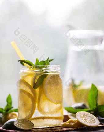冷新鲜的柠檬水透明的Jar与柠檬楔形和薄荷木背景冷新鲜的柠檬水透明的Jar与柠檬楔形和我