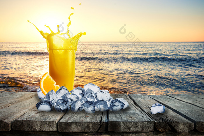 玻璃橙色汁与飞溅和冰木表格背景海玻璃汁站表格在的海日落的概念休息和假期玻璃橙色汁与飞溅和冰木表格巴克