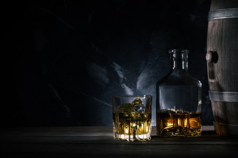 玻璃威士忌与冰玻璃水瓶和木桶木表格玻璃威士忌与冰玻璃水瓶和木桶