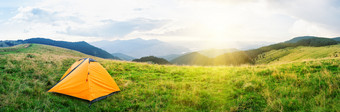 橙色帐篷草地与绿色草山下明亮的太阳多云的天空夏天景观全景橙色帐篷草地与绿色草山下明亮的