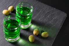 眼镜与苦艾酒和绿色橄榄黑暗背景眼镜与苦艾酒和绿色橄榄