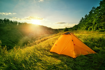 橙色旅游帐篷山以上的峡谷帐篷站的厚绿色草日落夏天景观的概念旅行自由和隐私橙色旅游帐篷山以上的峡谷