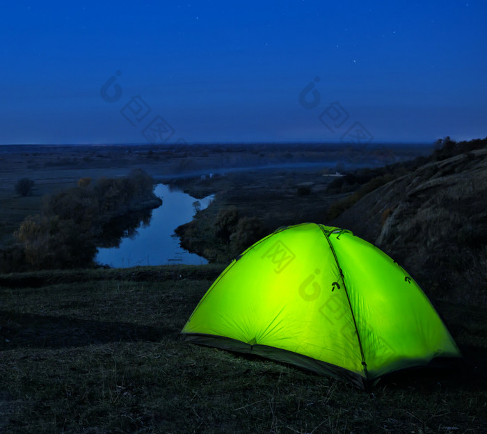 点燃从的内部绿色帐篷山以上的河晚上景观的概念自由隐私和旅行点燃从的内部绿色帐篷山以上河