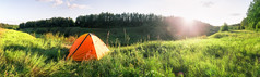 橙色旅游帐篷的绿色草下的设置太阳夏天景观的概念自由旅行和孤独橙色旅游帐篷的绿色草下的设置太阳