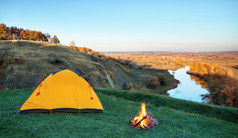 橙色旅游帐篷的绿色草的山以上的河清晰的天空夏天景观的概念隐私旅行和自由橙色旅游帐篷绿色草山以上河