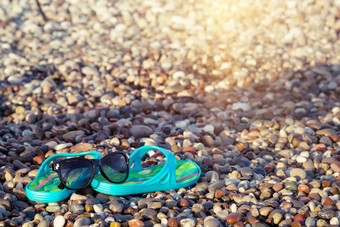 海滩蓝色的<strong>凉鞋</strong>和太阳镜的海滨石头假期和旅行概念海滩蓝色的<strong>凉鞋</strong>和太阳镜的海滨石头