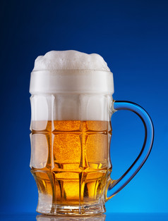 在上雕琢平面的杯子光啤酒与厚泡沫蓝色的背景在上雕琢平面的杯子光啤酒与泡沫蓝色的背景