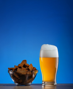 玻璃光啤酒和黑麦饼干透明的板蓝色的背景玻璃啤酒和黑麦饼干板蓝色的背景