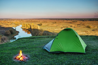 绿色旅游帐篷的绿色草的山以上的河清晰的天空夏天景观的概念隐私旅行和自由绿色旅游帐篷绿色草山以上河