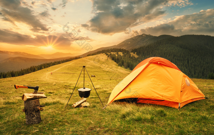 橙色帐篷与准备篝火日落橙色帐篷站平原的山附近的能火和日志与toporm夏天景观的概念隐私和旅行橙色帐篷与准备篝火日落