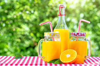 瓶和罐梅森与橙色汁绿色自然背景木表格红色的网纹桌布有机食物概念瓶和罐梅森与橙色汁绿色自然背景