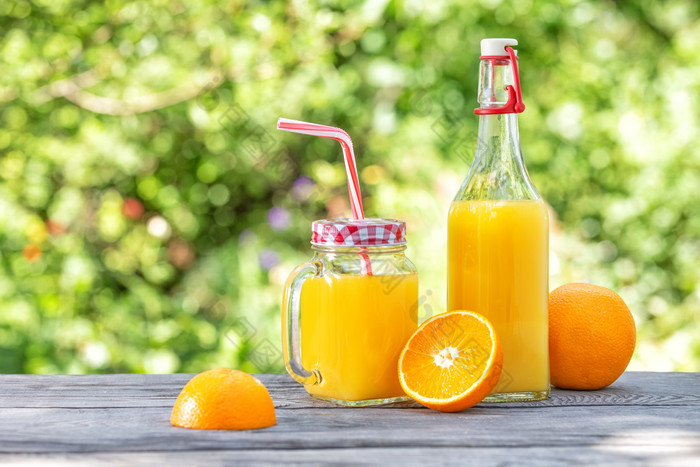 瓶和Jar与橙色汁和橙子木表格绿色自然背景夏天仍然生活瓶和Jar与橙色汁和橙子木表格