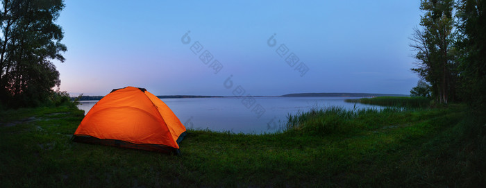 橙色帐篷的湖照亮从的内部帐篷的海岸蓝色的湖的早期早....夏天景观的概念旅行隐私自由橙色帐篷的湖