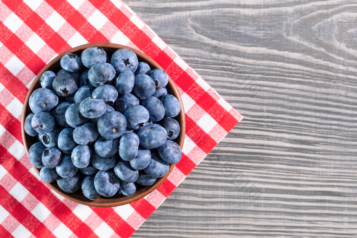 蓝莓粘土碗木表格与红色的网纹桌布视图从以上蓝莓粘土碗表格与红色的网纹桌布