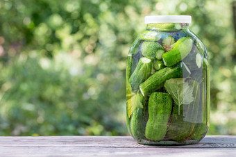 罐头自制的黄瓜玻璃Jar木表格自然绿色背景罐头自制的黄瓜玻璃Jar木表格