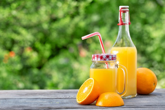 新鲜的橙色汁和切片橙子木表格自然绿色背景新鲜的橙色汁和切片橙子木表格