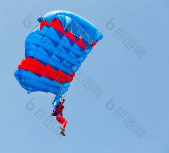 伞兵红色的西装下降下树冠降落伞的蓝色的天空伞兵红色的西装下降下树冠降落伞