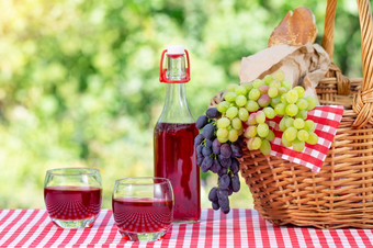 野餐<strong>篮子</strong>葡萄汁和魔杖红色的桌布阳光明媚的一天野餐概念野餐<strong>篮子</strong>葡萄汁和魔杖红色的桌布