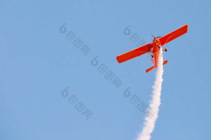 红色的滑翔机飞机发出白色烟蓝色的天空空气显示红色的滑翔机飞机发出白色烟蓝色的天空