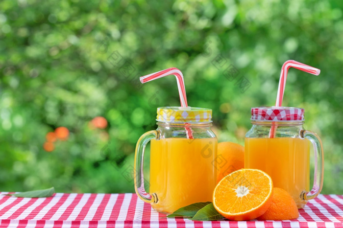 两个罐子橙色汁和一半橙色叶子自然绿色背景两个罐子橙色汁和一半橙色叶子
