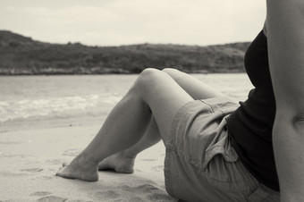 女孩坐着的边缘的海滩悲观的一天